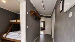 Een gang met een stapelbed, grijze wanden en een betegelde vloer.