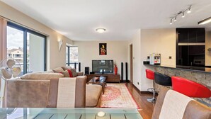 Een moderne woonkamer met een bank, televisie en een glazen salontafel.