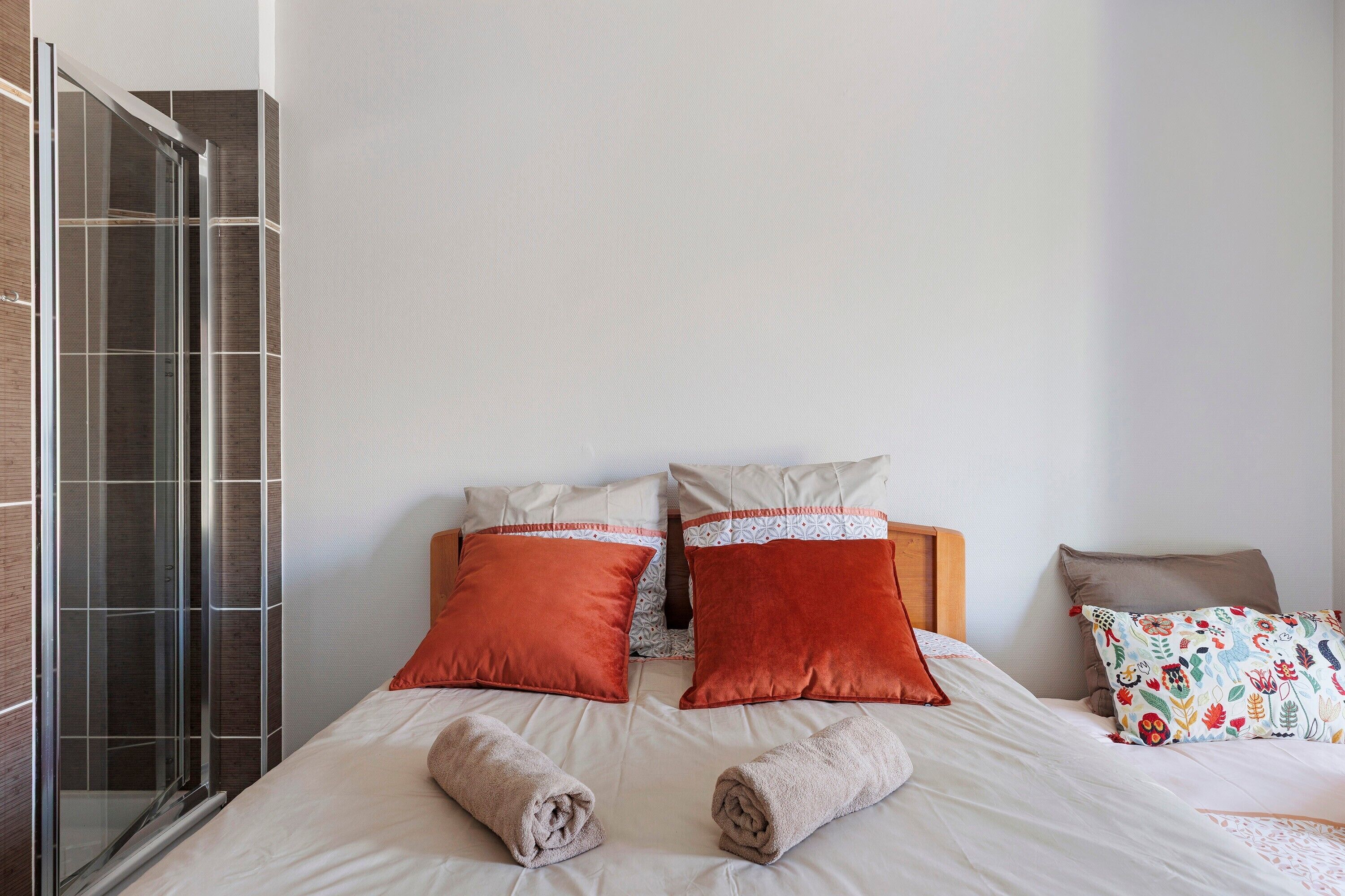 Une chambre d’hôtel avec un lit, deux oreillers, une douche et une serviette.
