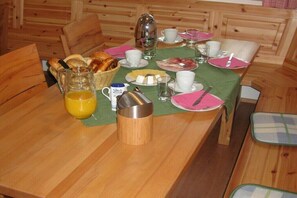 Ein Esszimmer mit Holztisch, gedeckt mit Frühstücksgebäck, Brot und einer Kaffeekanne.