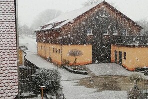 Ein schneebedecktes Gebäude mit geneigtem Dach und einem kleinen Teich davor.