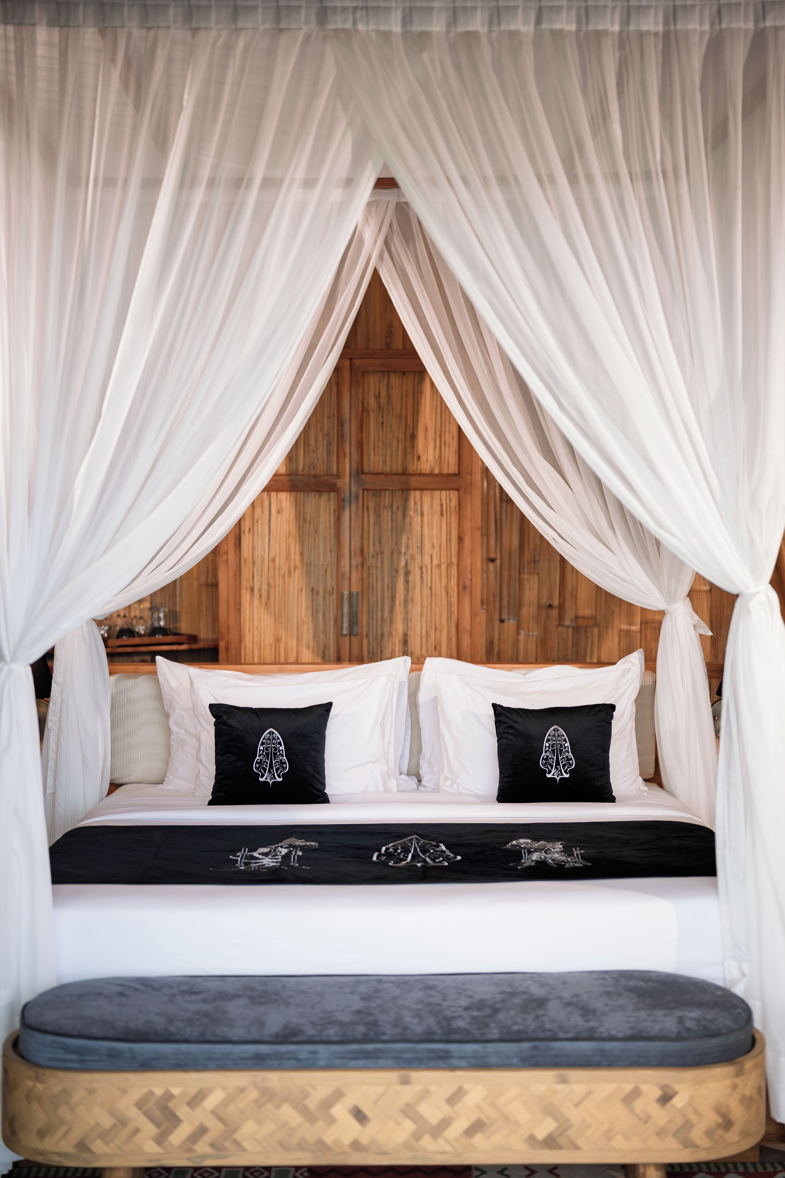 A bed with a canopy, pillows with a crest design, and a wooden headboard.