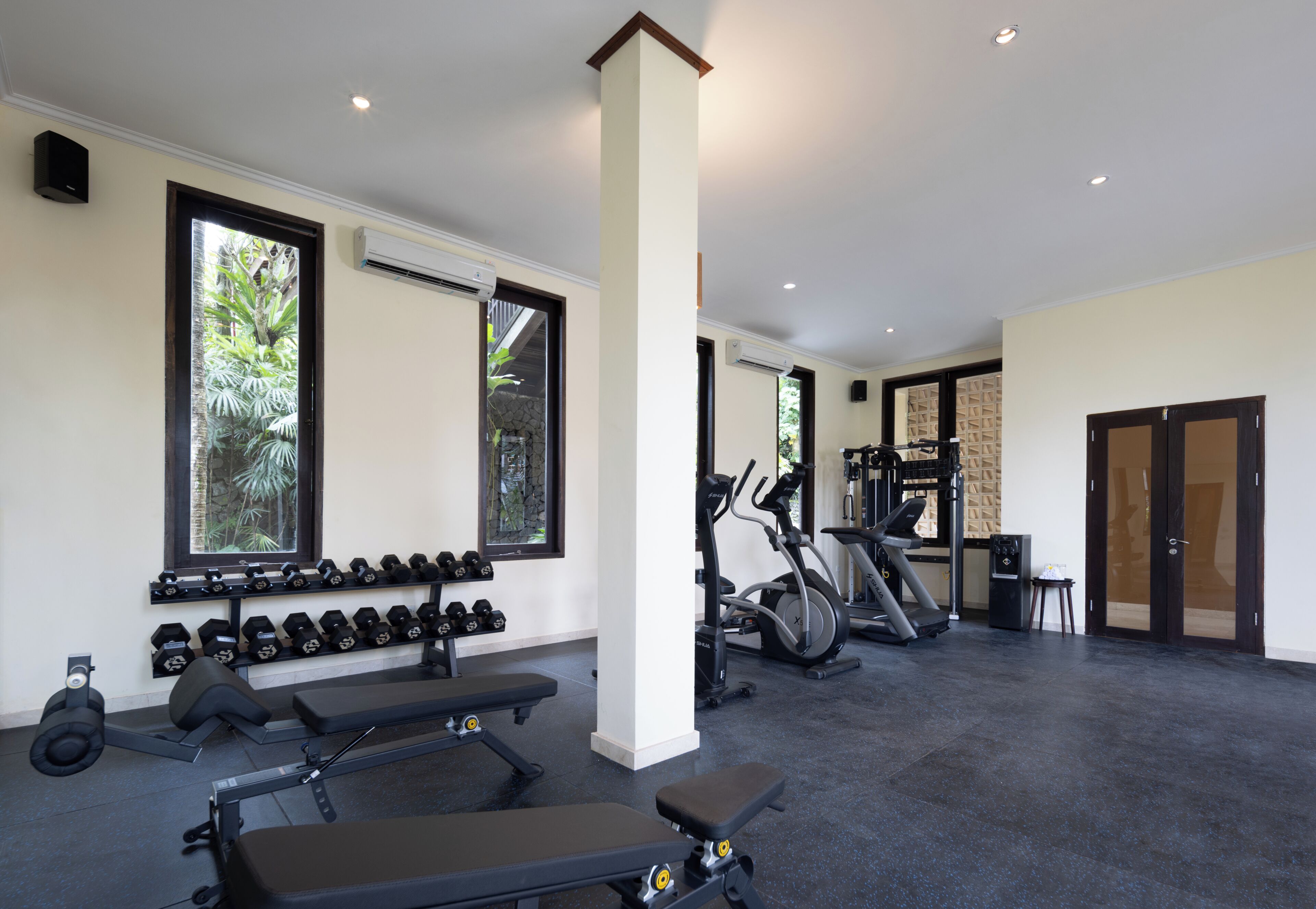 Un gimnasio con equipo de ejercicio, mancuernas, cintas de correr y bicicletas estáticas.