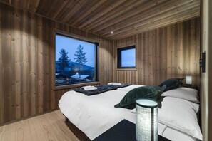 A wooden-paneled bedroom with a large window, a bed, and a bedside table. - Nyørk Chalet, Hemsedal (Hemsedal)