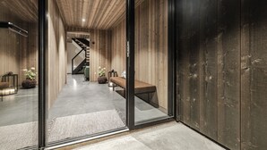 Un interno moderno con pannelli in legno, una scala, una panca e una porta in vetro.