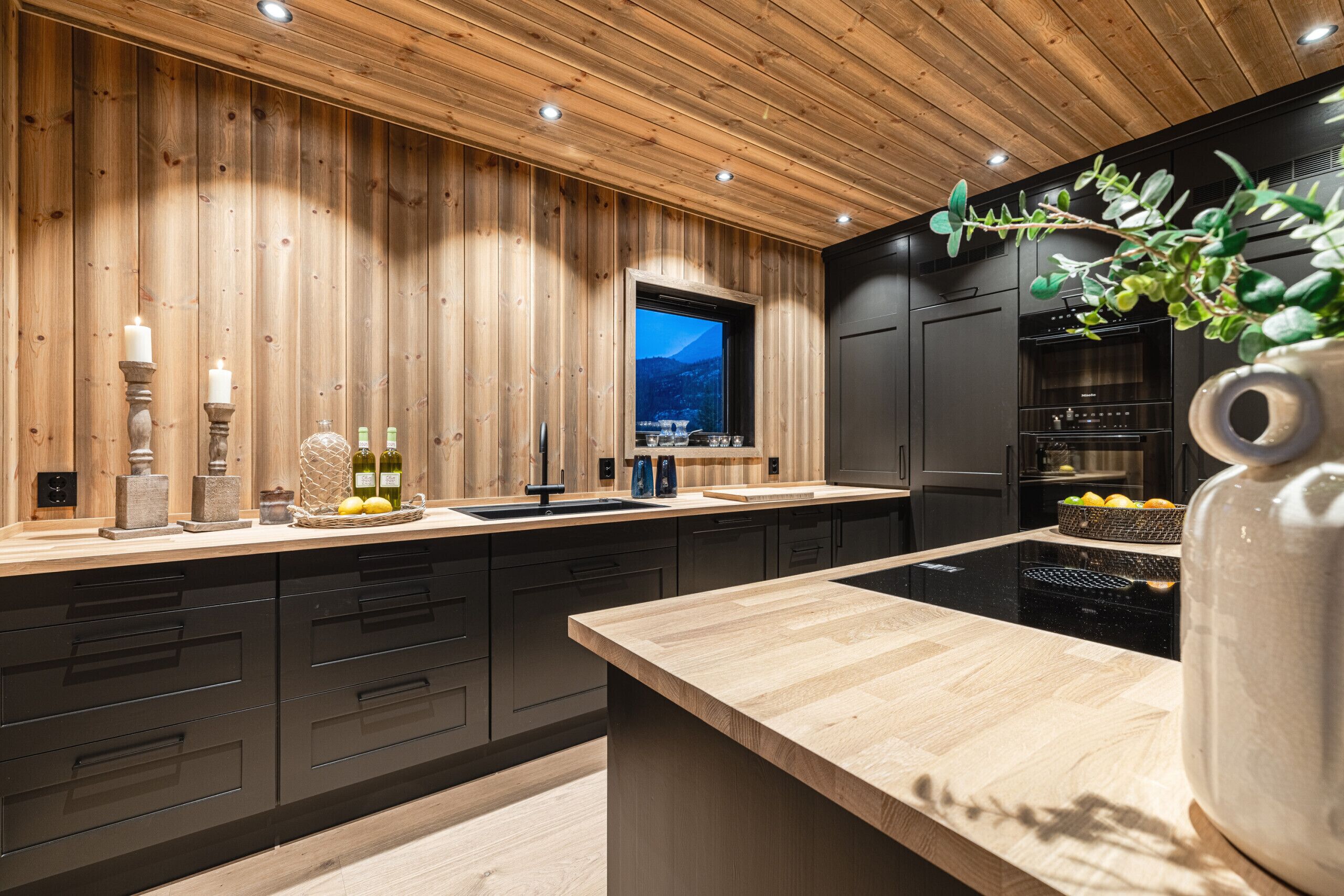 Eine moderne Küche mit Holzvertäfelung, einem großen Fenster und einem eingebauten Backofen.