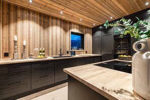 A modern kitchen with wooden paneling, a large window, and a built-in oven. - Nyørk Chalet, Hemsedal (Hemsedal)