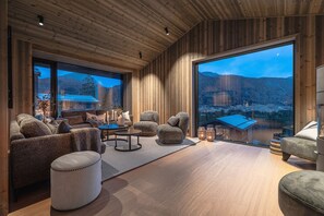 A modern living room with wooden walls and large windows, featuring a sofa, armchairs, and a coffee table. - Nyørk Chalet, Hemsedal (Hemsedal)