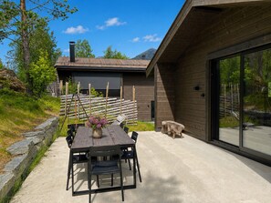 A modern outdoor dining area with a table and chairs, a wooden fence, and a mountain backdrop. - Nyørk Chalet, Hemsedal (Hemsedal)