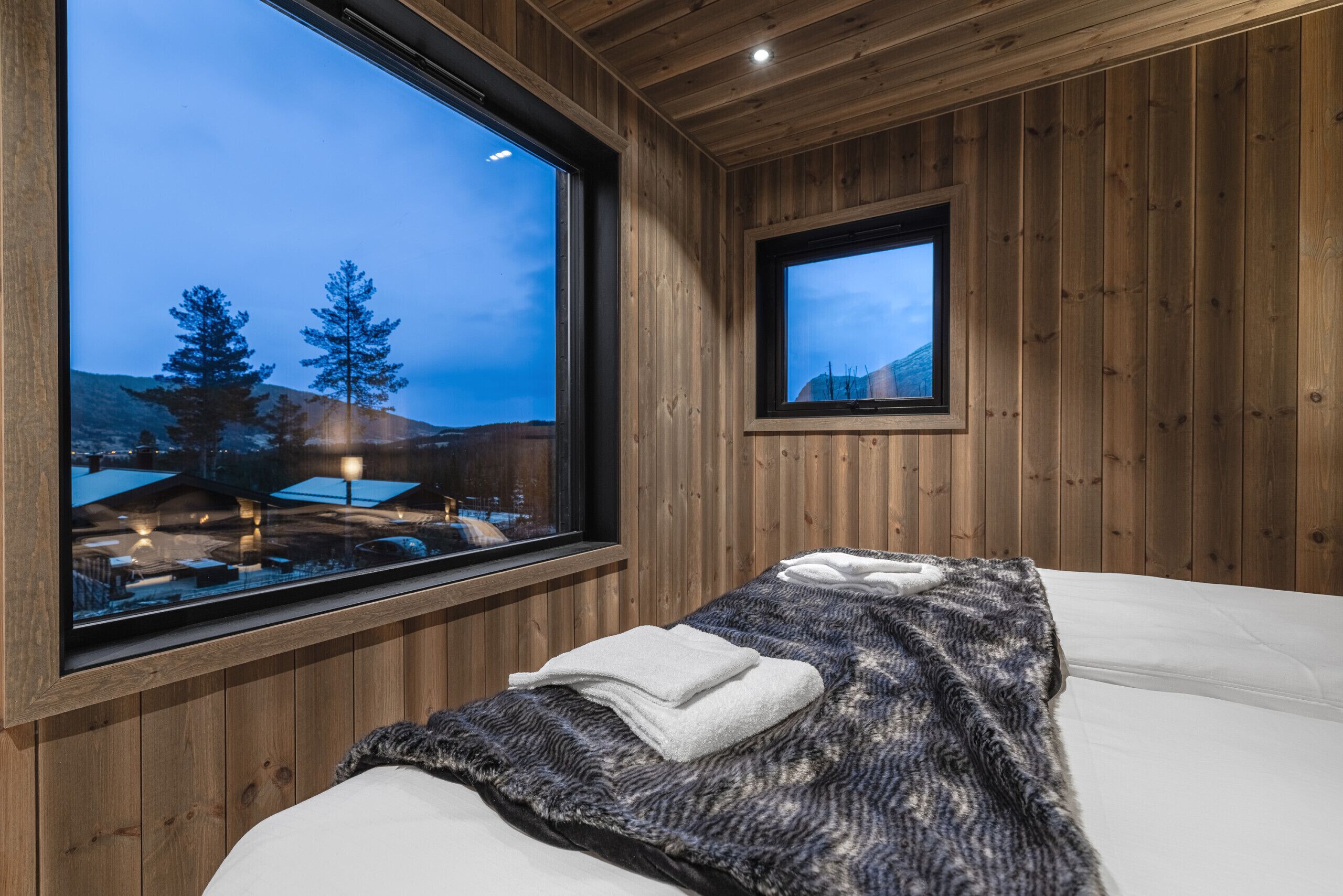 A wooden room with a bed, a window, and a television.