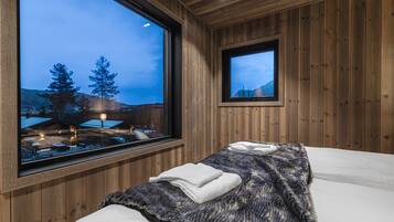 A wooden room with a bed, a window, and a television.