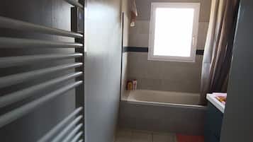 A bathroom with a bathtub, a window, and a ceiling fan.