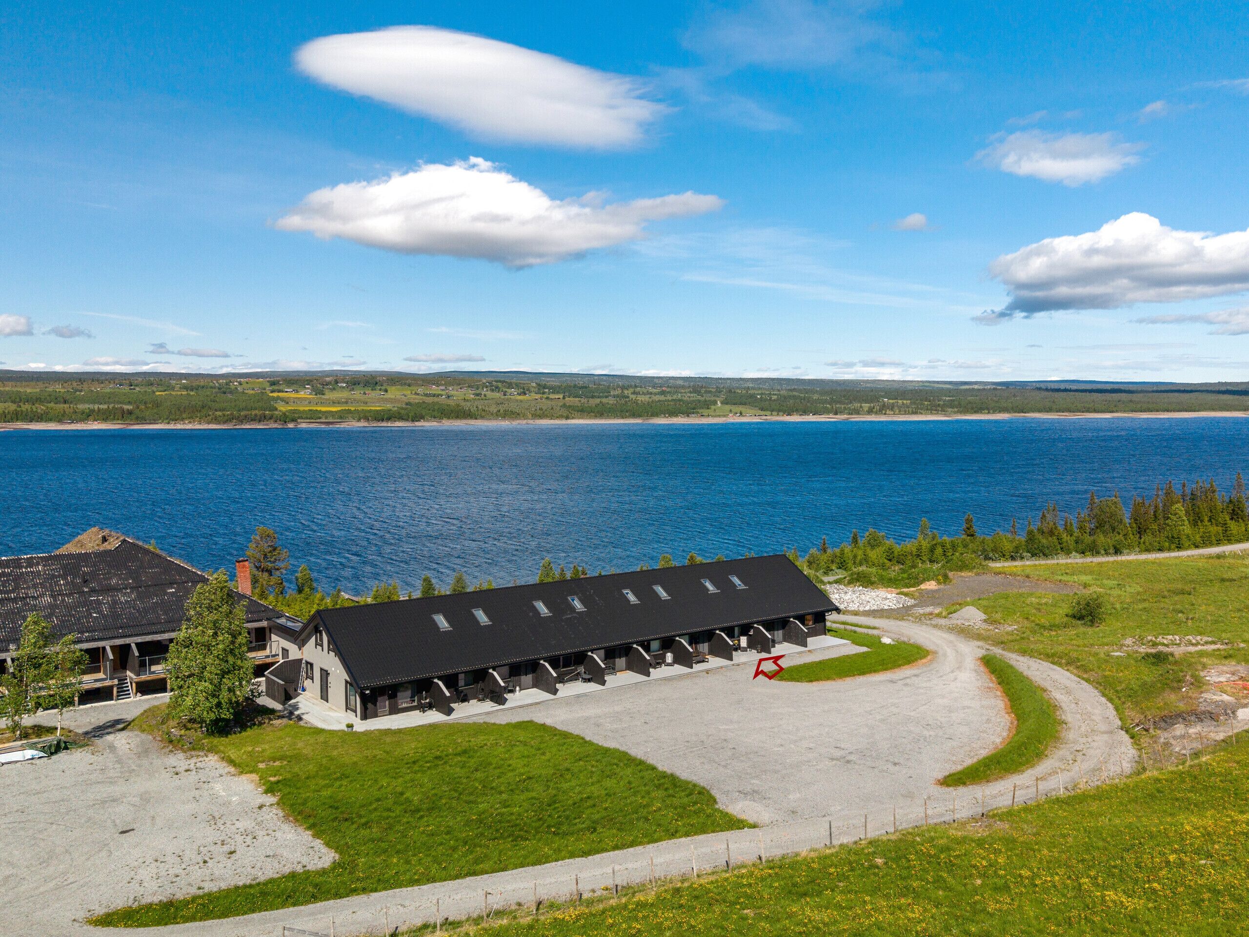 A lakeside building with a long corridor and a parking area.