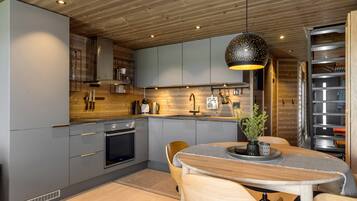 A modern kitchen with grey cabinets, wooden ceiling, and a dining area with a table and chairs.