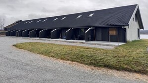 A modern building with a sloped roof and multiple covered areas, likely for parking or storage. - Modern apartment in Glomsrud Golsfjellet west (Gol)