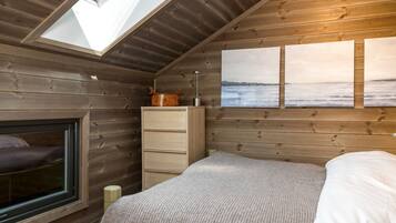 Ein Schlafzimmer mit Oberlicht, Holzwänden, einem Bett, einer Kommode und einem Fenster.