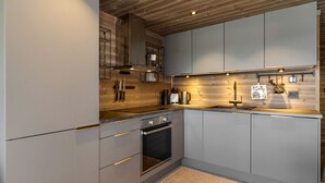A modern kitchen with grey cabinets, a built-in oven, and a wooden ceiling. - Modern apartment in Glomsrud Golsfjellet west (Gol)