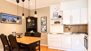 Une cuisine moderne avec des meubles blancs, une table à manger en bois et des luminaires suspendus.