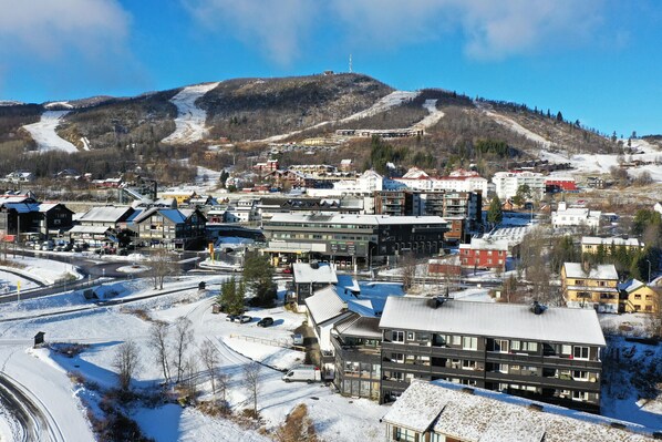 Eine Stadt mit einem Skigebiet im Hintergrund, Mehrstöckige Gebäude und eine Mischung aus Wohn- und Geschäftsgebäuden.