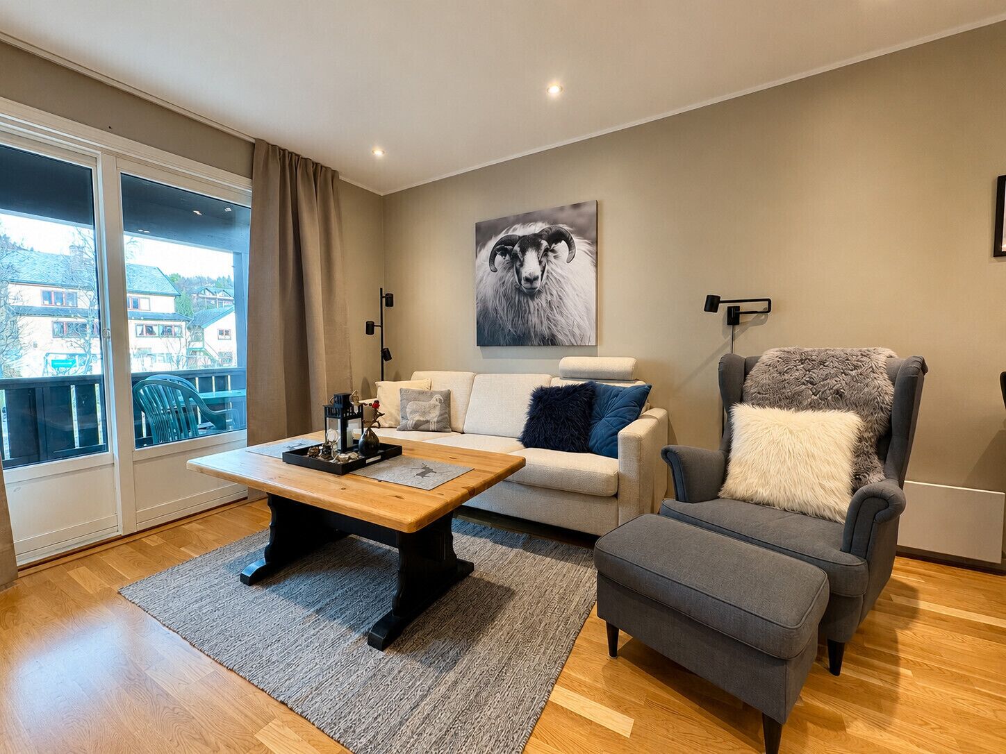 Een moderne woonkamer met een bank, fauteuil, salontafel en een groot raam met uitzicht.