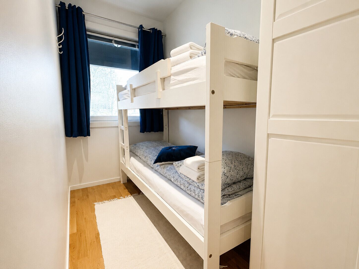 Dormitorio con literas, ventana, cortinas y una alfombra.