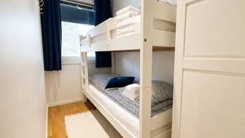 Dormitorio con literas, ventana, cortinas y una alfombra.