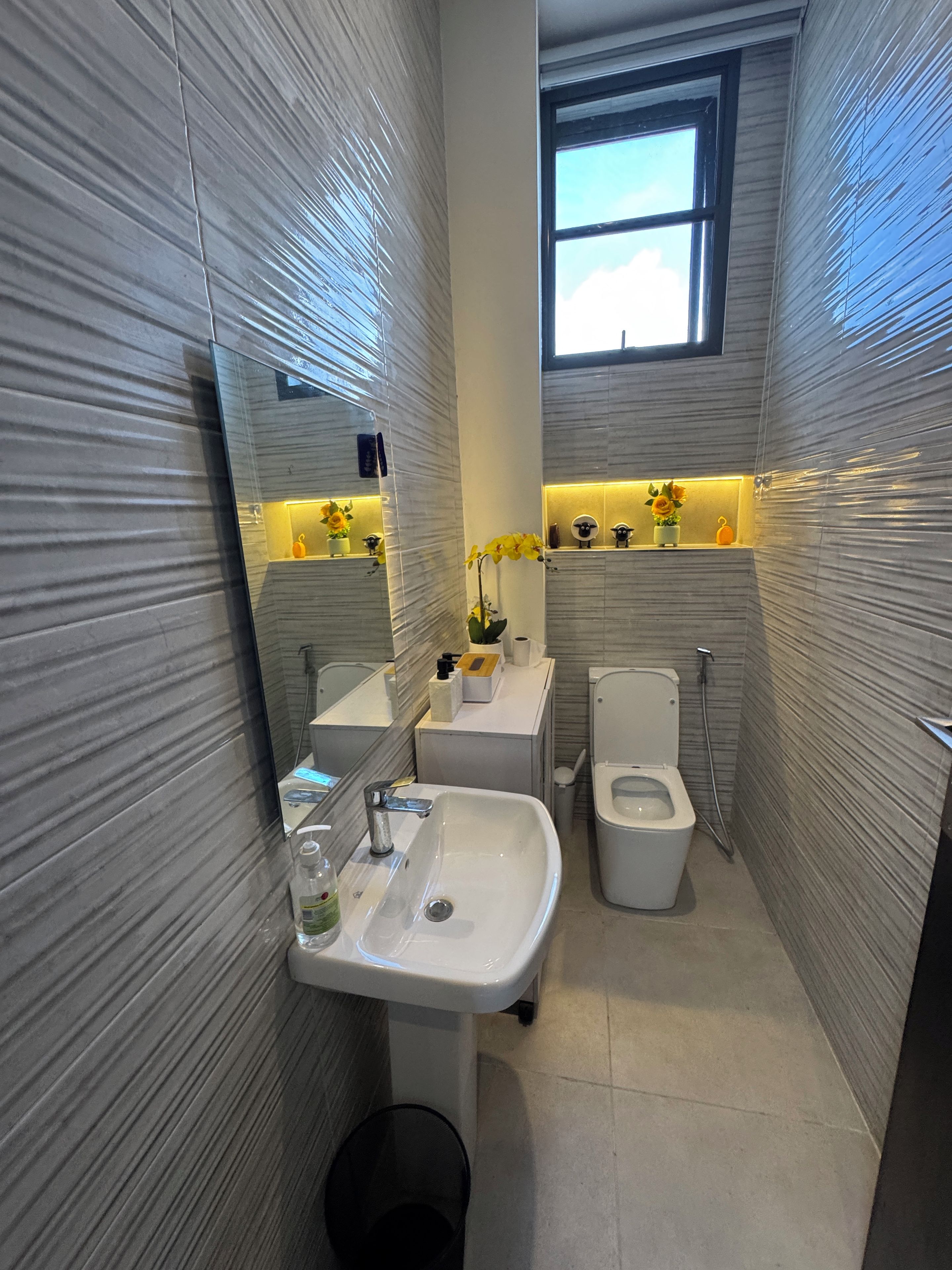 A compact bathroom with a sink, toilet, and a window.