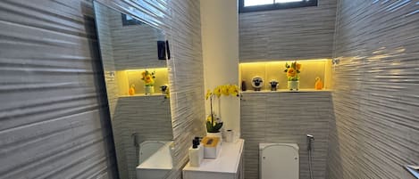 A compact bathroom with a sink, toilet, and a window.