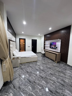 A modern hotel room with a bed, a TV, a desk, and a bathroom. - Martins court (Lagos)