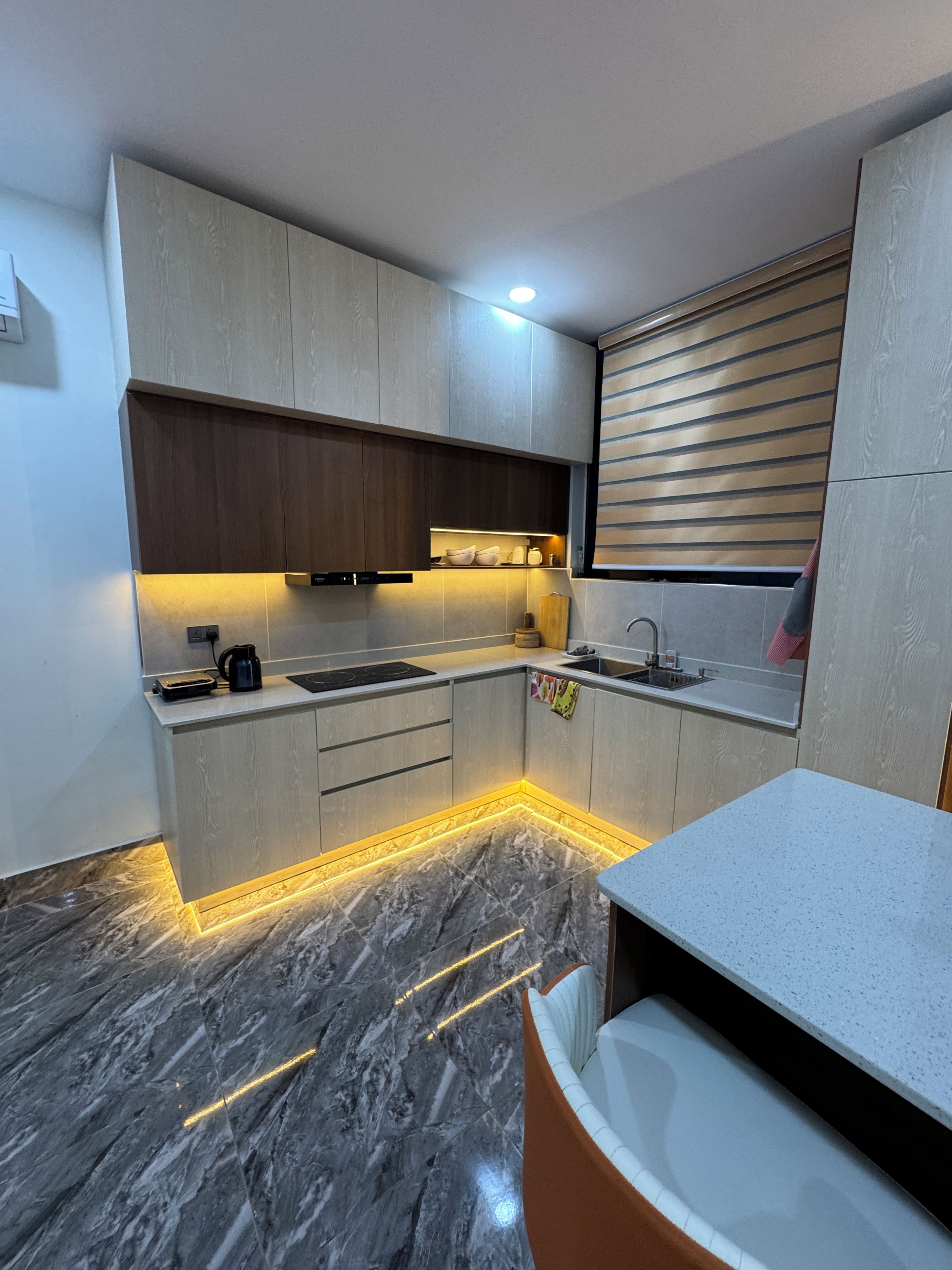 Una cocina moderna con suelo de mármol, armarios de madera y horno empotrado.