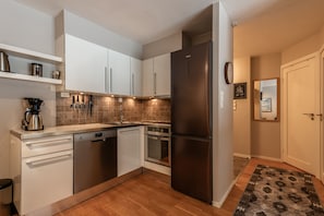 A modern kitchen with white cabinets, stainless steel appliances, and a patterned rug.
