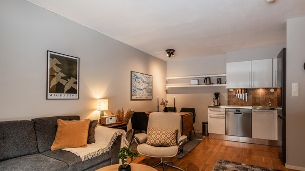 Een moderne woonkamer met een bank, salontafel en een eethoek met stoelen.