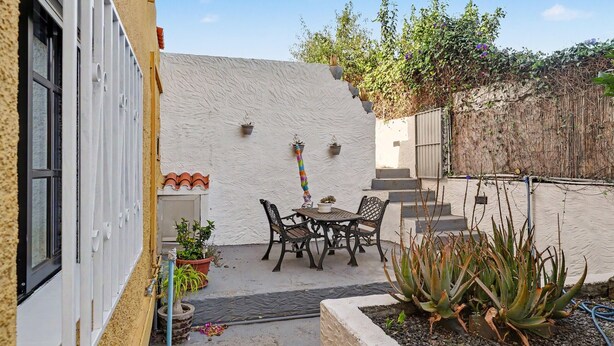 A patio with a table and chairs, surrounded by potted plants and a small garden area.