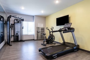 A fitness center with cardio equipment, a wall-mounted TV, and a window with blinds. - Echo Suites Extended Stay by Wyndham Middleburg (Middleburg)