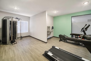 Uma academia com esteira, bicicleta ergométrica e aparelho de musculação.