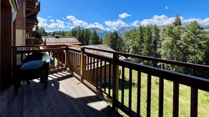 Ein Holzbalkon mit Blick auf Berge und Bäume.