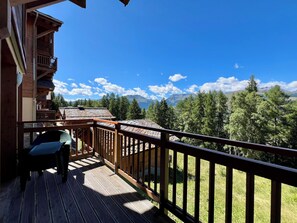 Ein Holzbalkon mit Blick auf Berge und Bäume.
