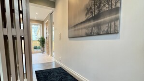 A hallway with a dark rug, a painting of trees, and a wooden partition. - Exclusive top apartment, central location in Bergen. (Bergen)