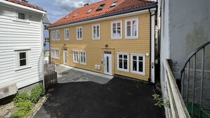 A two-story building with a red-tiled roof, white-framed windows, and a small balcony. - Exclusive top apartment, central location in Bergen. (Bergen)