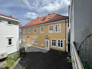 A two-story building with a red-tiled roof, white-framed windows, and a small balcony. - Exclusive top apartment, central location in Bergen. (Bergen)