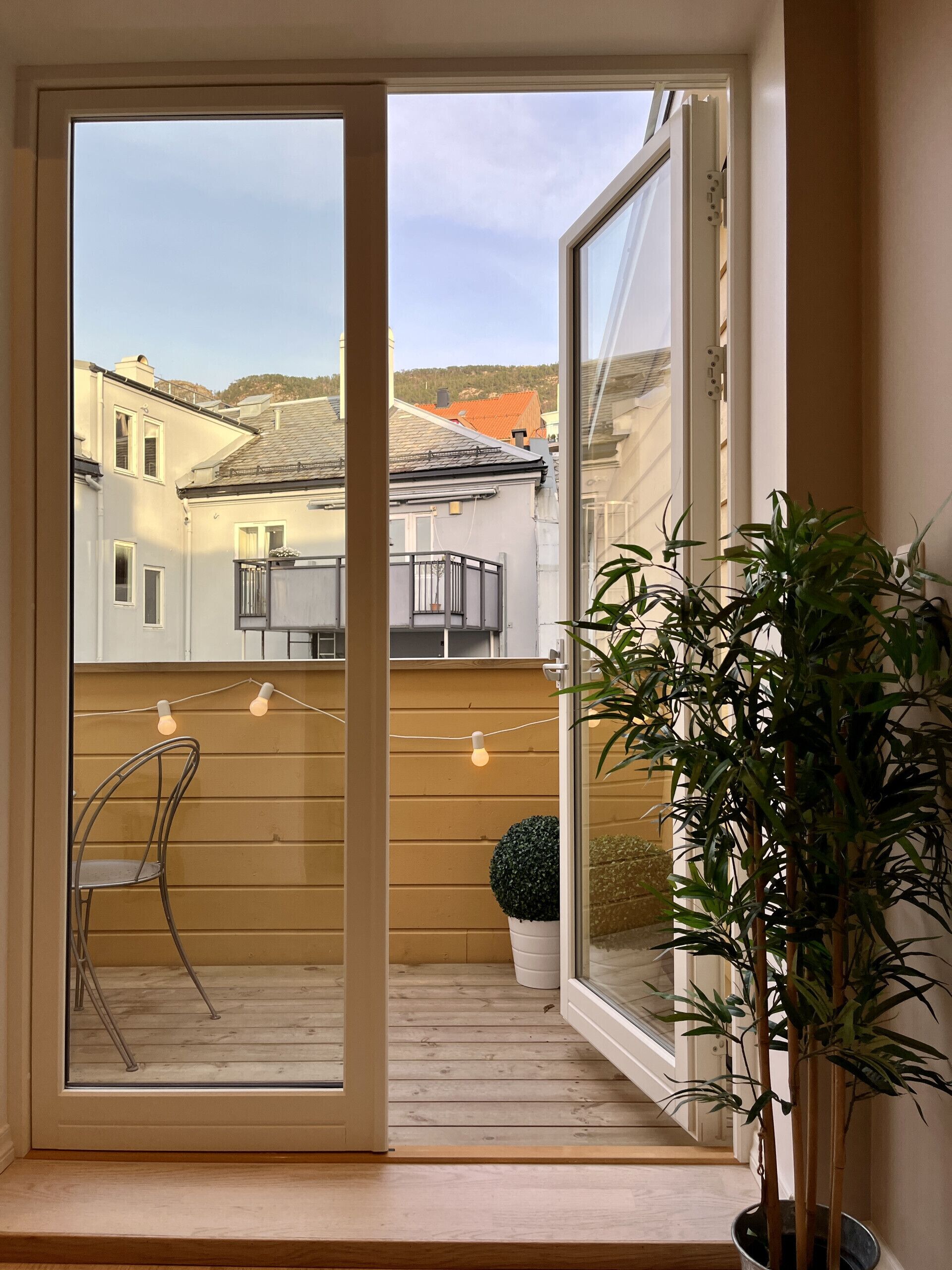 Een kamer met een glazen schuifdeur naar een balkon, een bloempot en een stoel.