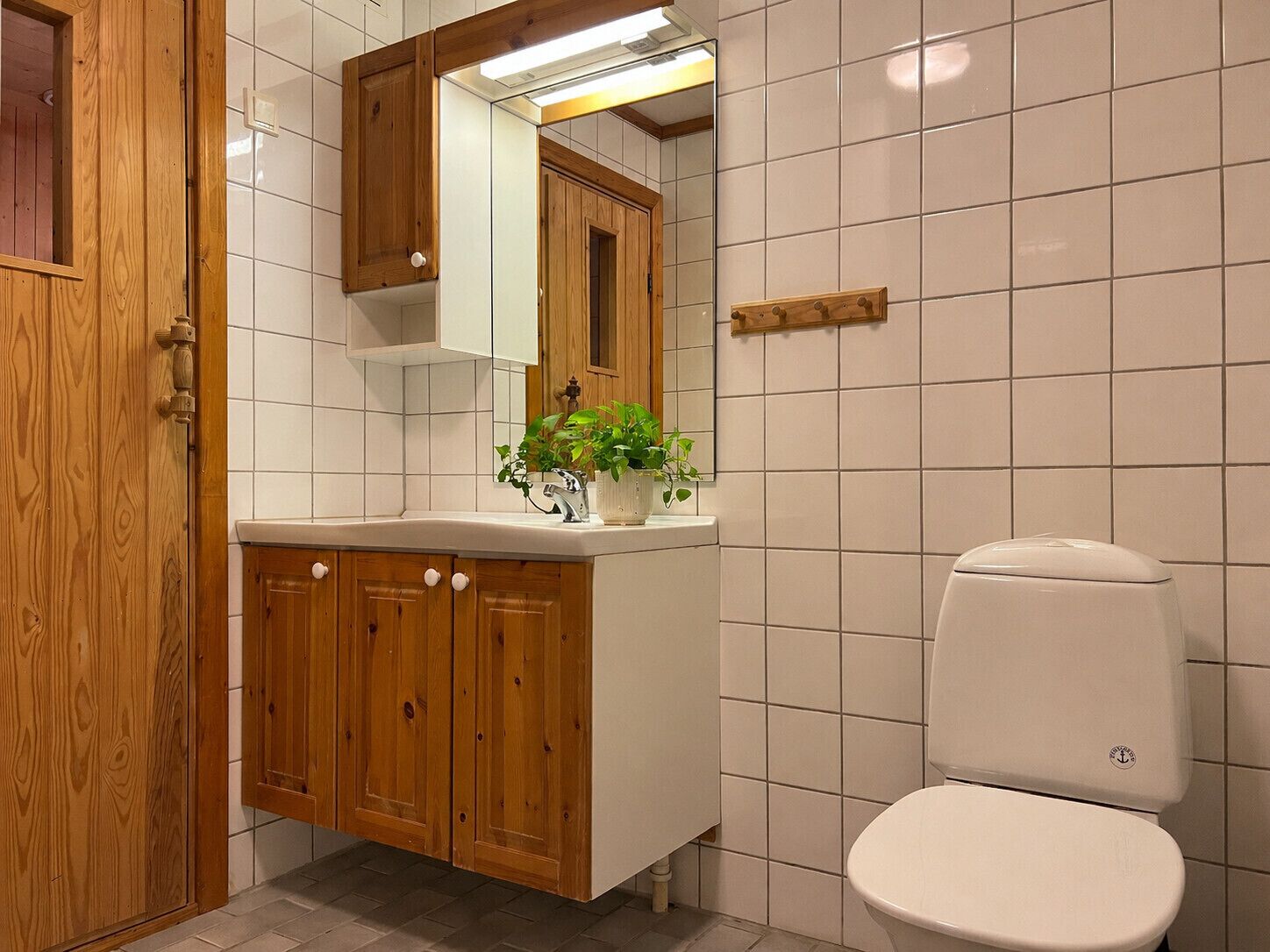 Un bagno con un mobile bagno in legno, un WC bianco e uno specchio sopra il lavandino.