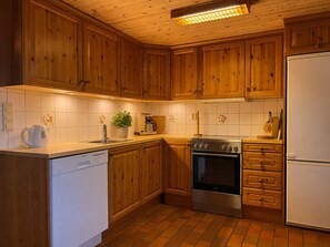 Una cocina con gabinetes de madera, lavavajillas, horno y refrigerador.