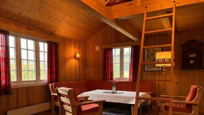 Ein gemütliches Zimmer mit Holzvertäfelung, einem runden Tisch und einer Couch.