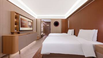 A hotel room with a large bed, a TV mounted on a wooden console, and a circular light fixture on the wall.