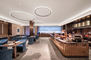 Un restaurante moderno con luces de techo redondas, asientos azules y una barra con una máquina de café.