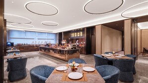 Un restaurante moderno con zona de bar, mesas redondas y sillas azules.