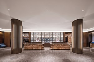 A lobby with two reception desks, a glass display case, and a blue sofa.