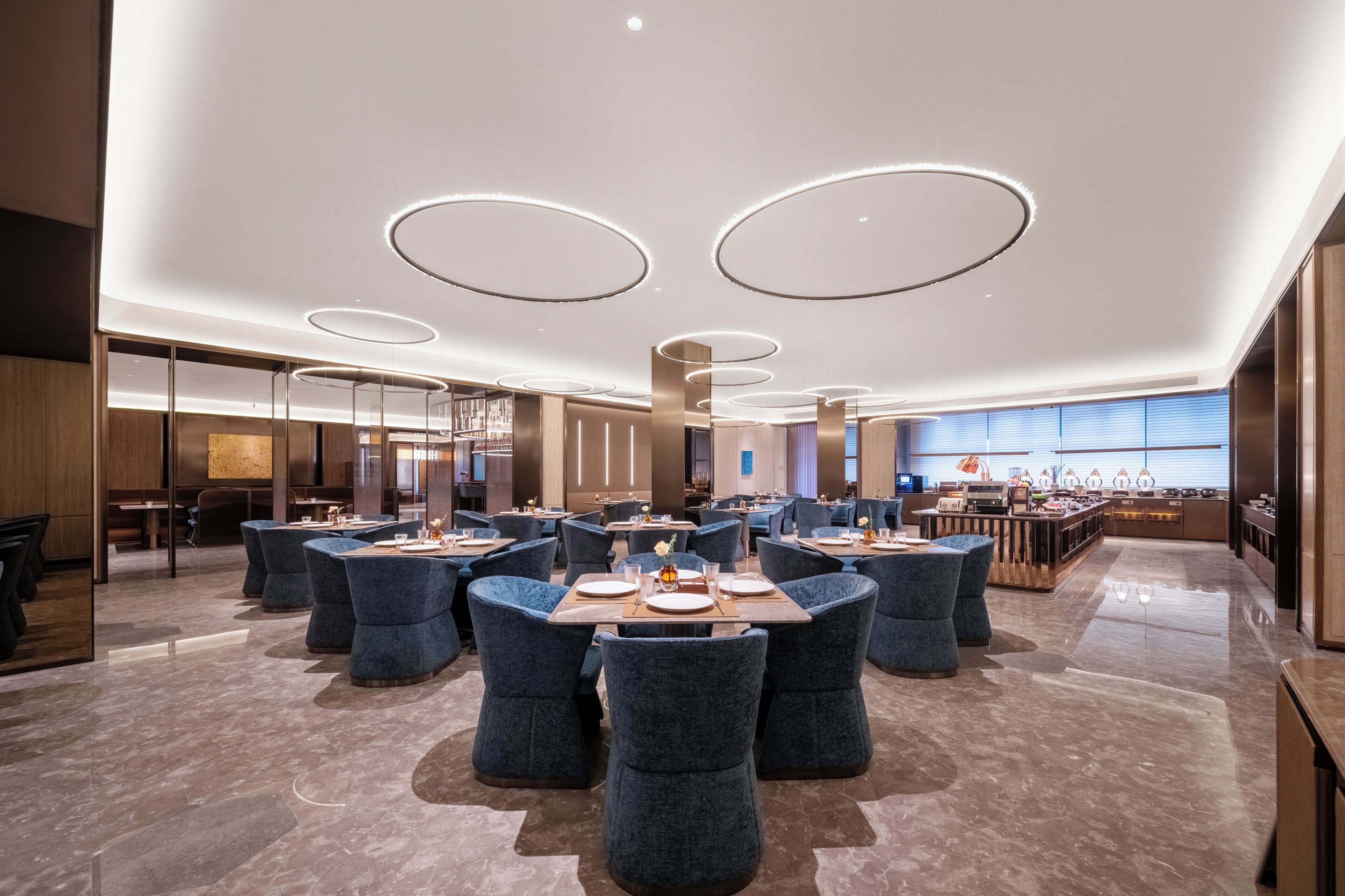 A modern dining area with round tables, blue chairs, and a bar in the background.