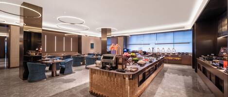 A modern hotel lobby with a central bar area, seating arrangements, and a large window providing natural light.